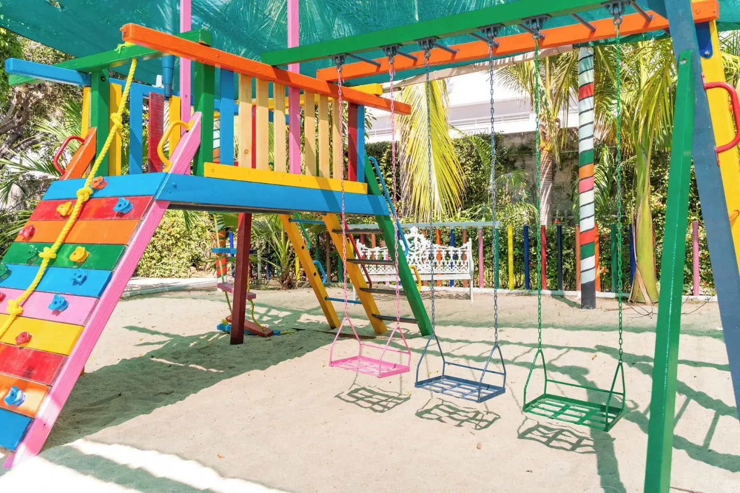 Swings and climbing wall in the shaded playground at Hotel Castillo Huatulco & Beach Club.