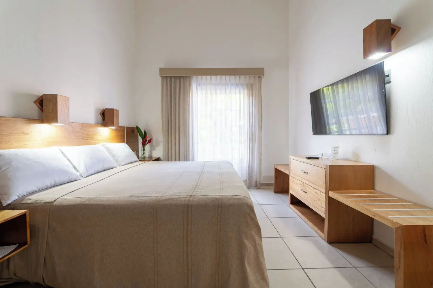 Family Room bed with wall-mounted TV at Hotel Castillo Huatulco & Beach Club.