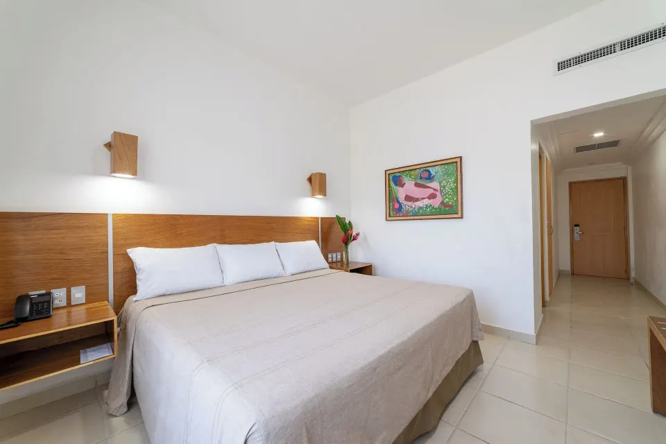 Standard Room with king bed, bedside tables, artwork, and entry hall at Hotel Castillo Huatulco & Beach Club.