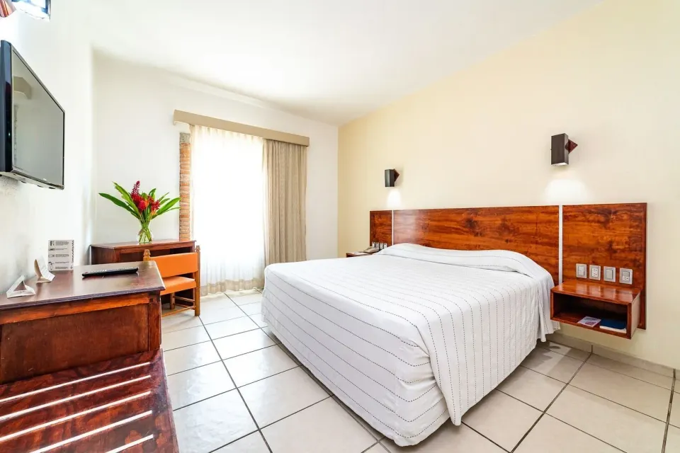 Standard Room with king bed, TV, desk, and window at Hotel Castillo Huatulco & Beach Club.