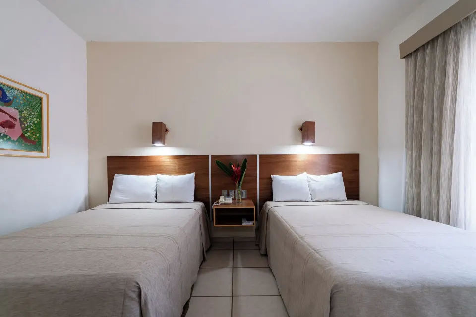 Standard Room with two beds, shared nightstand, wall lights, and window at Hotel Castillo Huatulco & Beach Club.