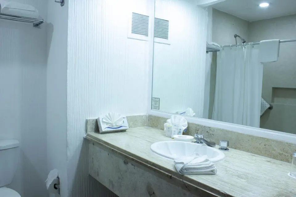 Standard room bathroom vanity and shower curtain at Hotel Castillo Huatulco & Beach Club.