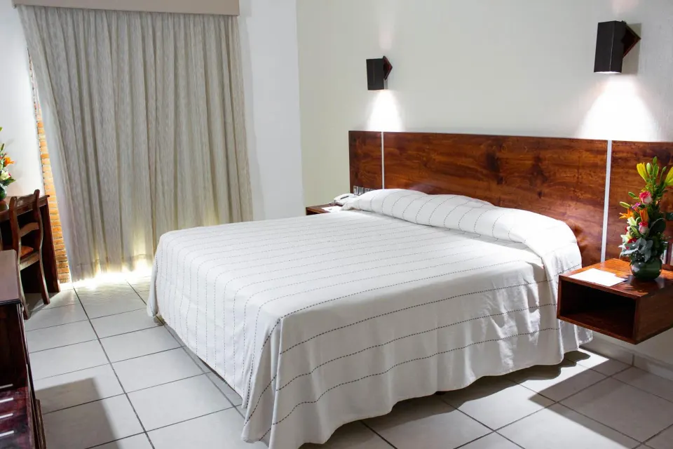 Standard room with a king bed and curtains at Hotel Castillo Huatulco & Beach Club.