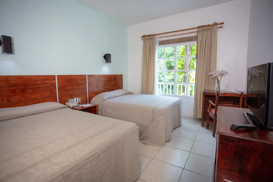 Standard room with two beds, window, desk, and TV at Hotel Castillo Huatulco & Beach Club.