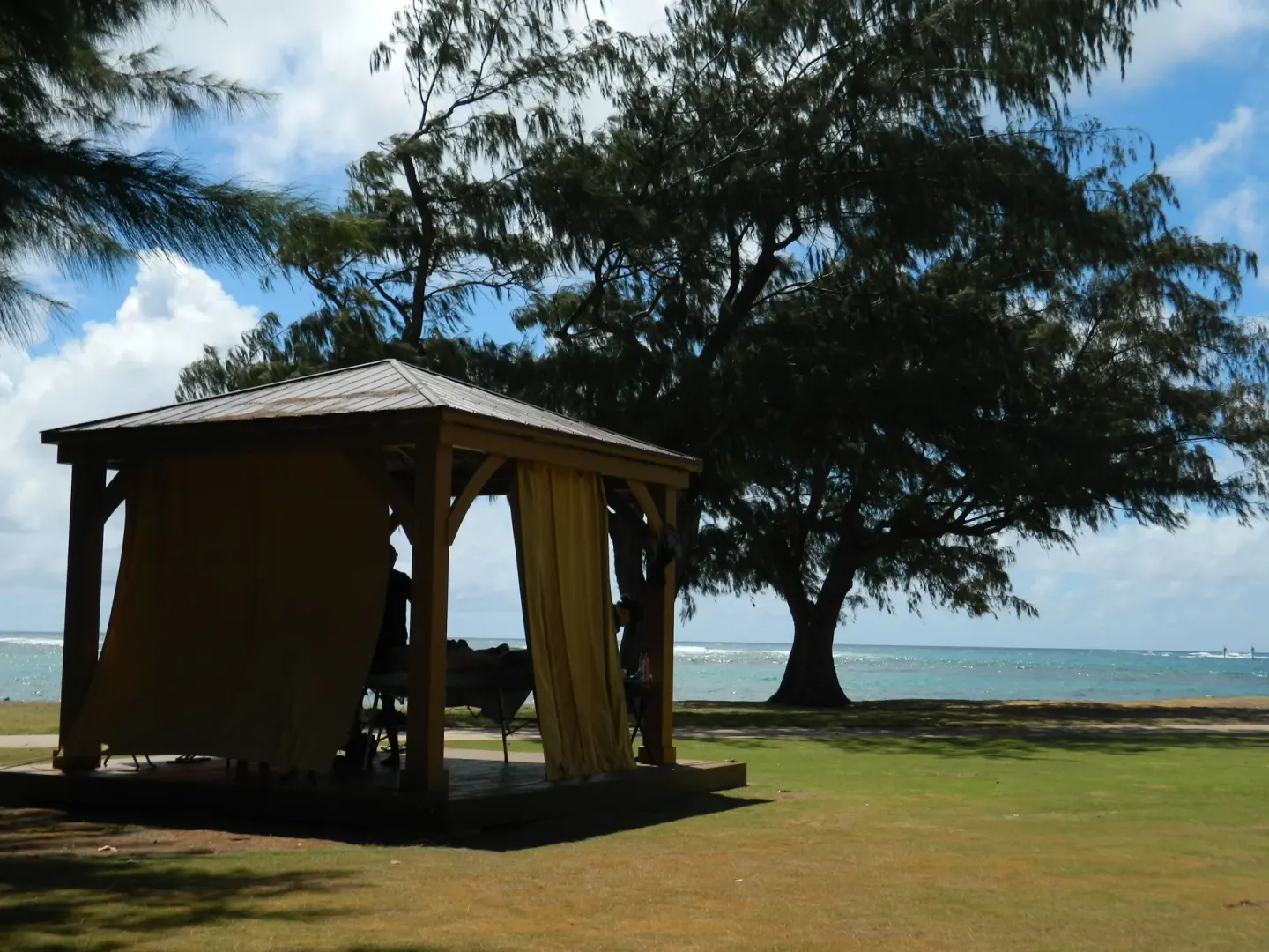Lawn massage cabana with trees and ocean beyond at Hotel Coral Reef.
