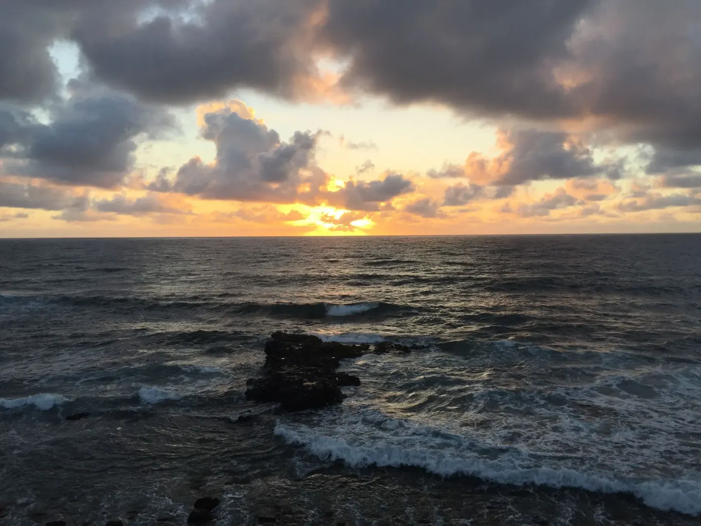 Ocean sunset with rocky surf viewed from Hotel Coral Reef.