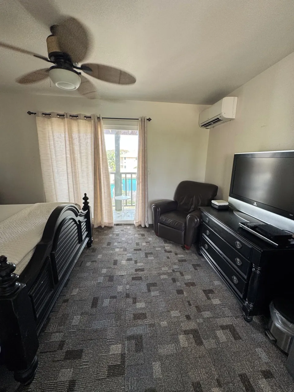 Economy Room City View with bed, armchair, TV, balcony door, and AC at Hotel Coral Reef.