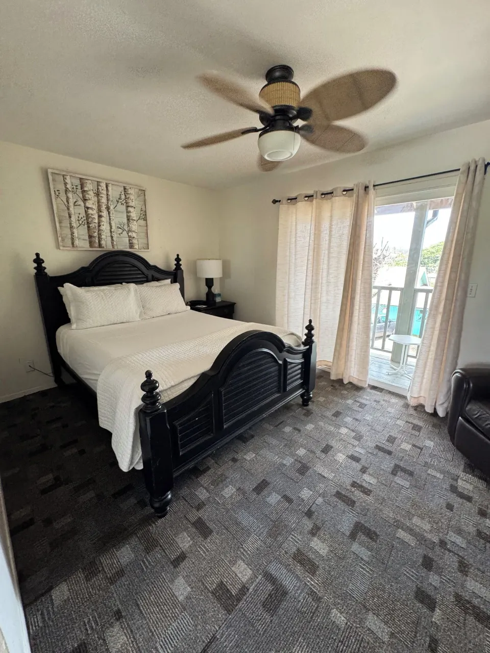 Economy Room City View queen bed beside a glass balcony door at Hotel Coral Reef.