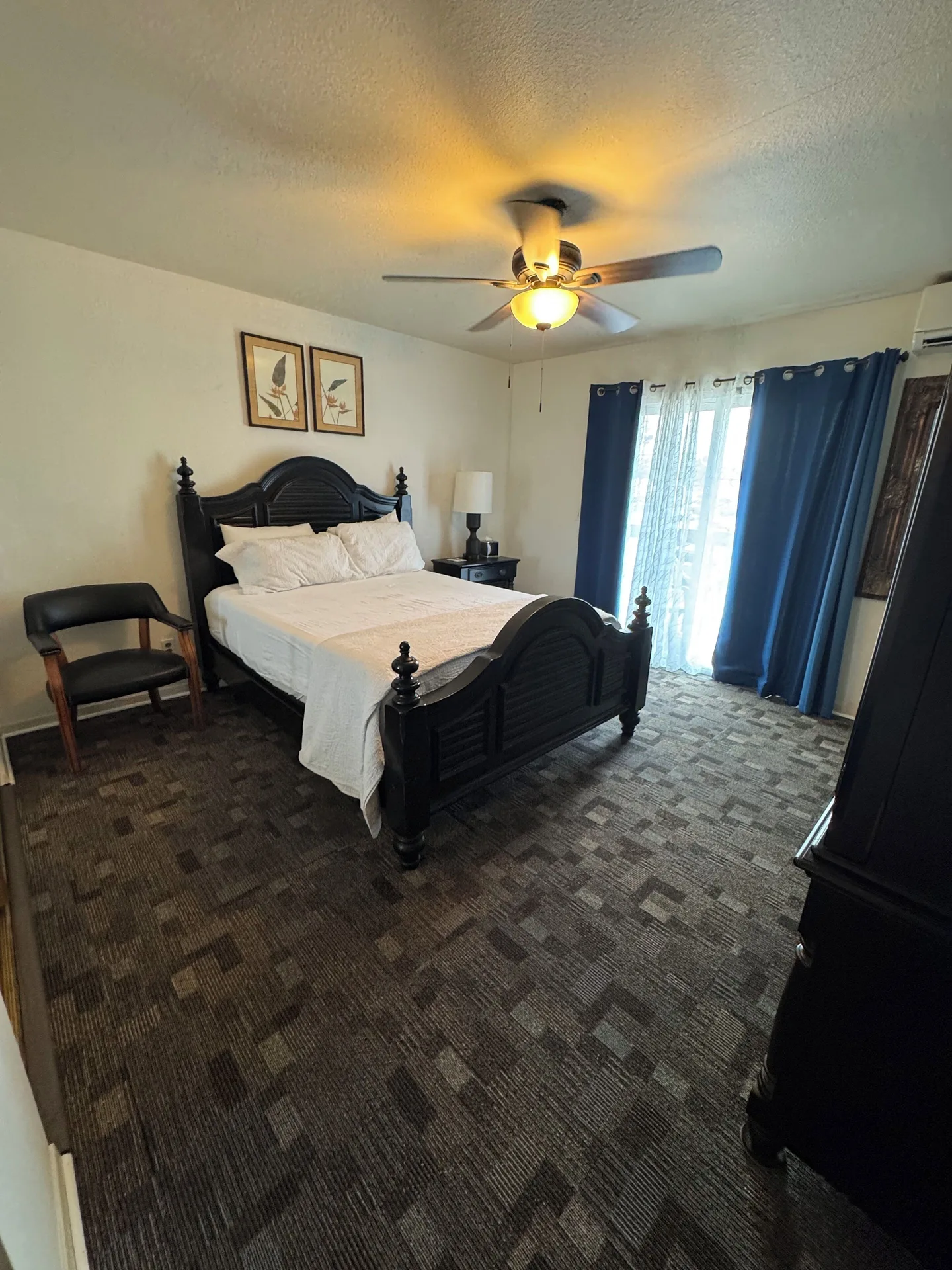 Economy Room City View bed with blue curtains and ceiling fan at Hotel Coral Reef.