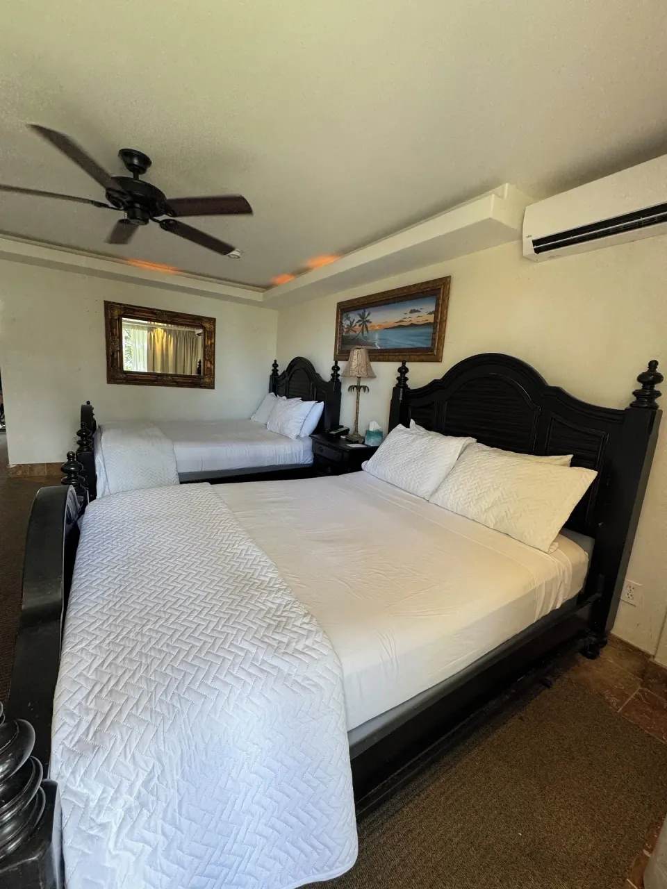 Oceanfront room with two beds, dark wood frames, and wall art at Hotel Coral Reef.