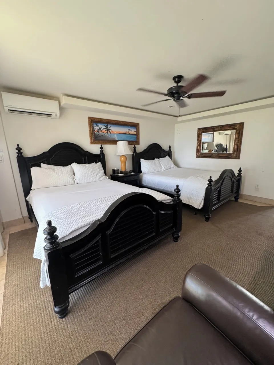 Oceanfront room with two beds, lamp, mirror, and ceiling fan at Hotel Coral Reef.
