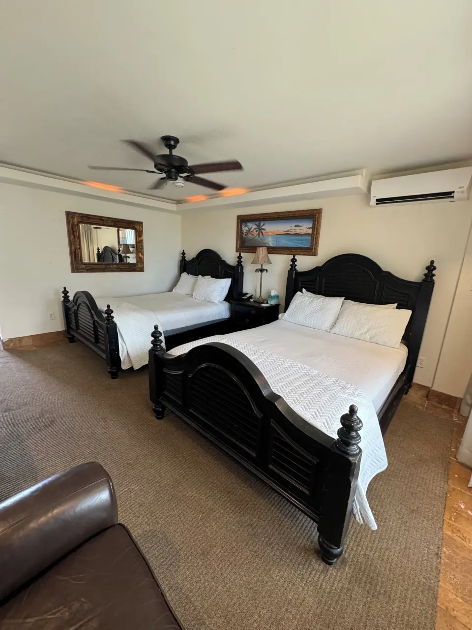 Oceanfront room with two beds, mirror, armchair, and air conditioner at Hotel Coral Reef.