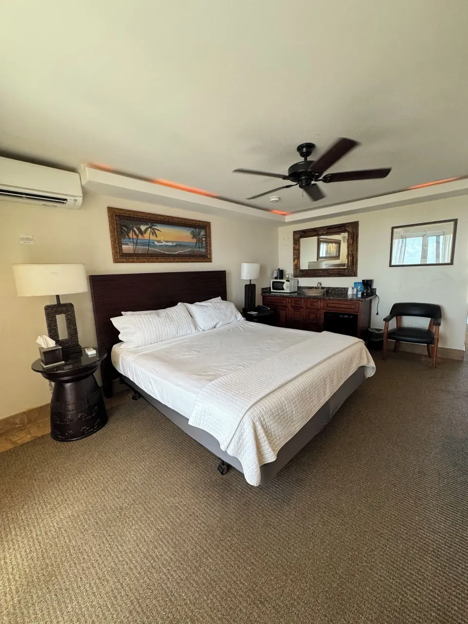 Panoramic Room king bed with kitchenette-style counter and mirror at Hotel Coral Reef.