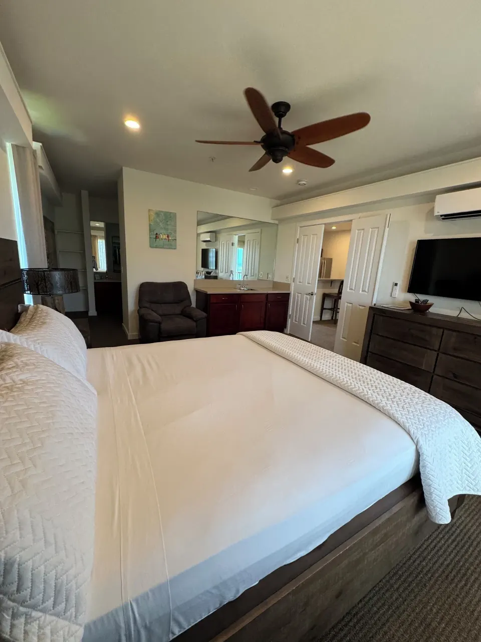 Premium Suite bedroom with large bed, TV, dresser and vanity at Hotel Coral Reef.