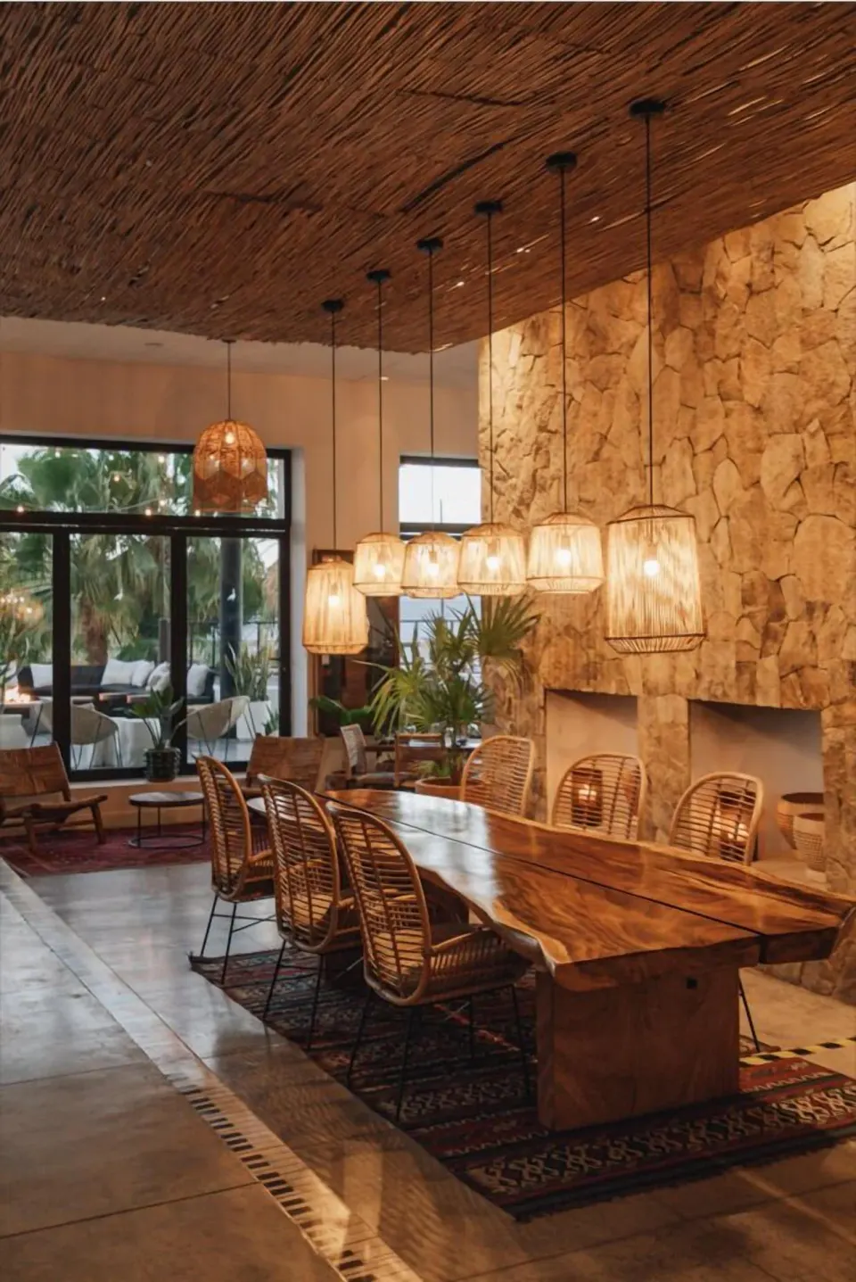 Long wooden communal table with woven chairs and pendant lights at Hotel El Ganzo.