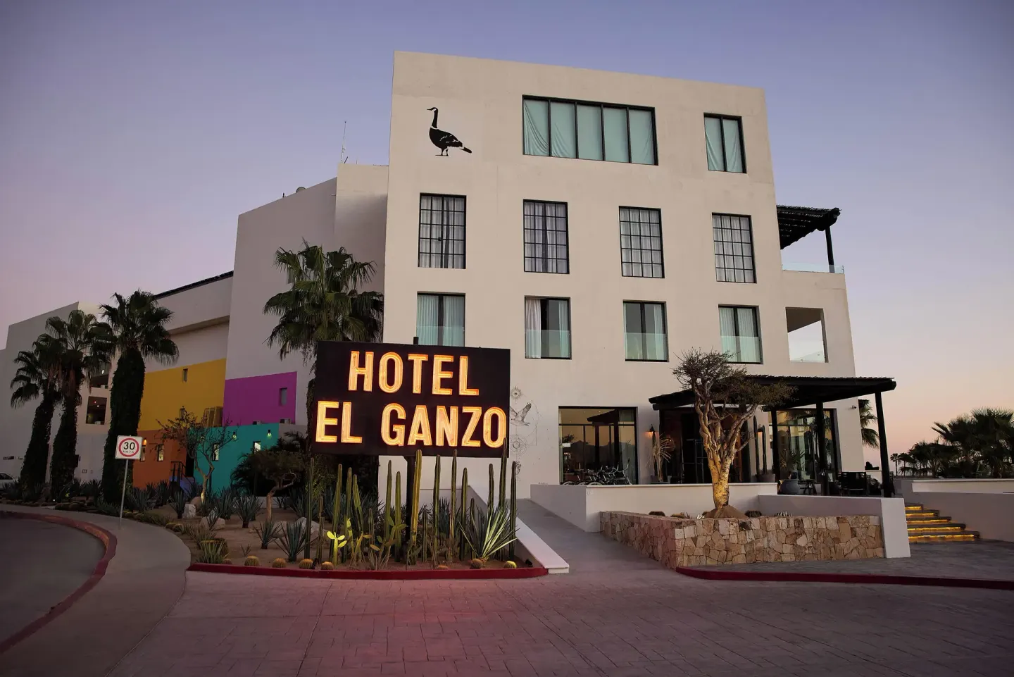 Hotel El Ganzo exterior with illuminated roadside sign at dusk.