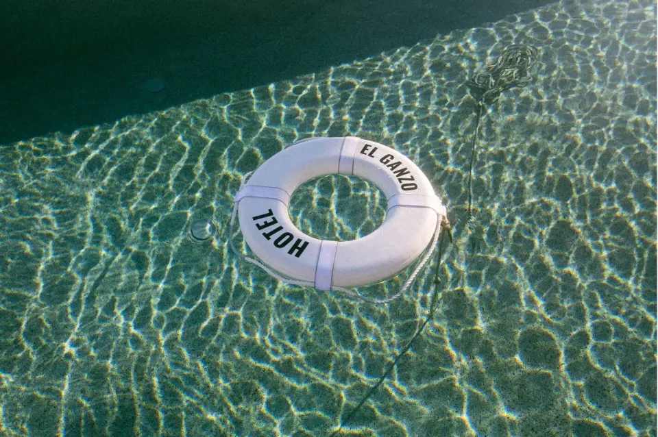 White Hotel El Ganzo life ring floating in a clear swimming pool.