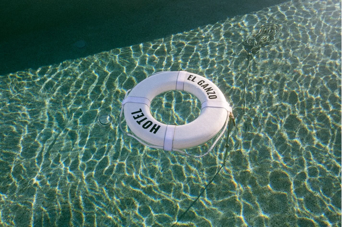 White Hotel El Ganzo life ring floating in a clear swimming pool.
