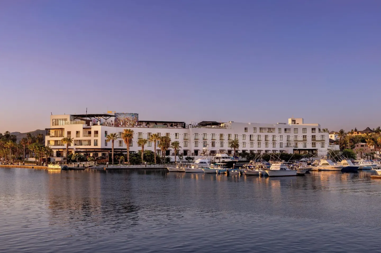 Hotel El Ganzo exterior beside a marina with boats at dusk.