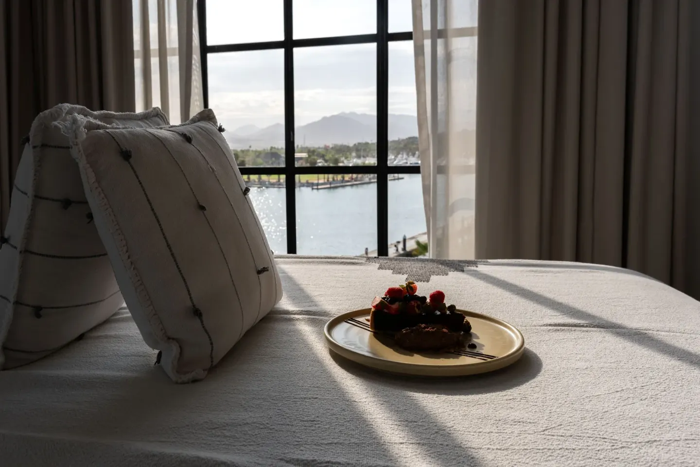 Captain's Suite bed with dessert plate and marina view at Hotel El Ganzo.