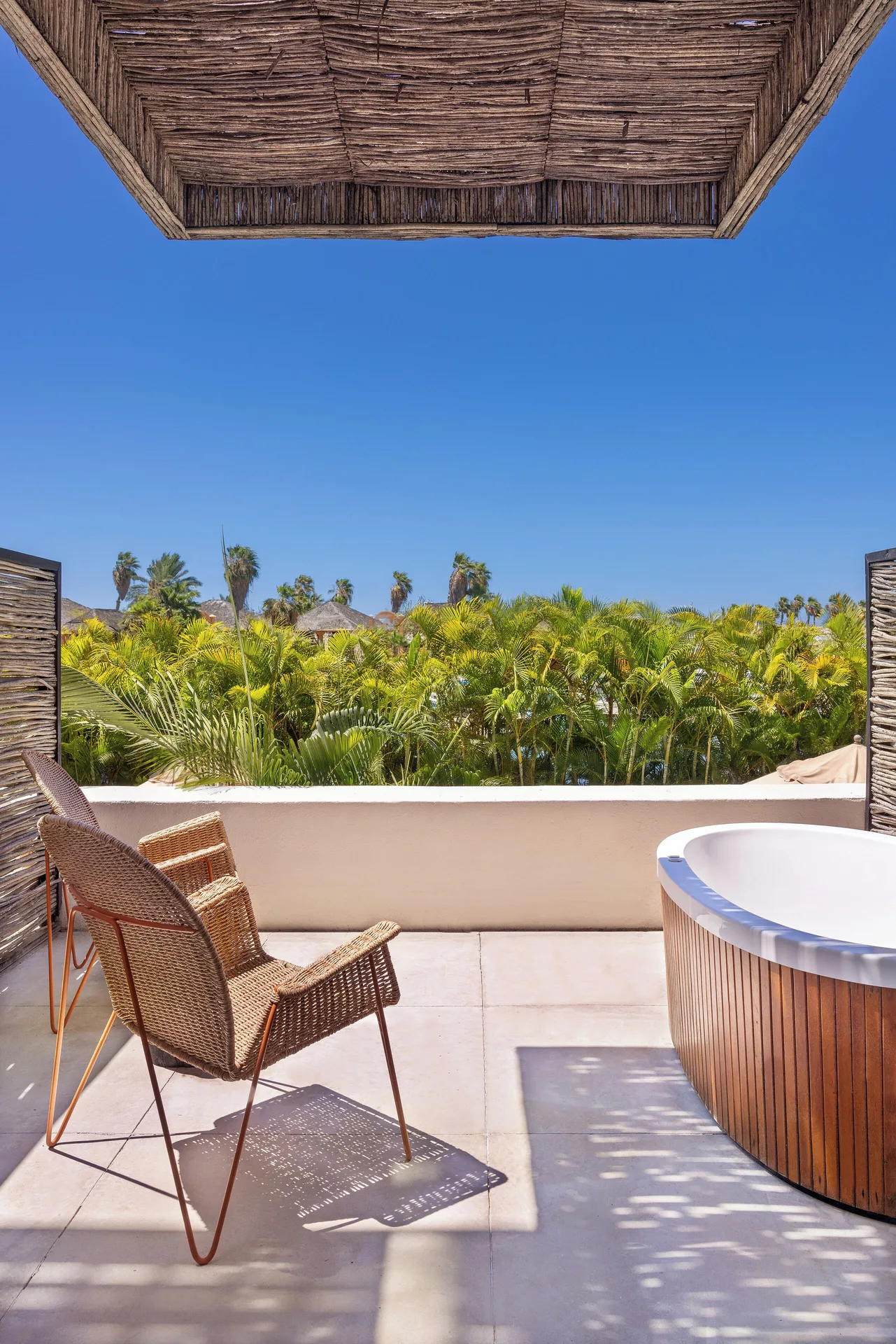 Jacuzzi room terrace with outdoor tub, woven chair and palm views at Hotel El Ganzo.