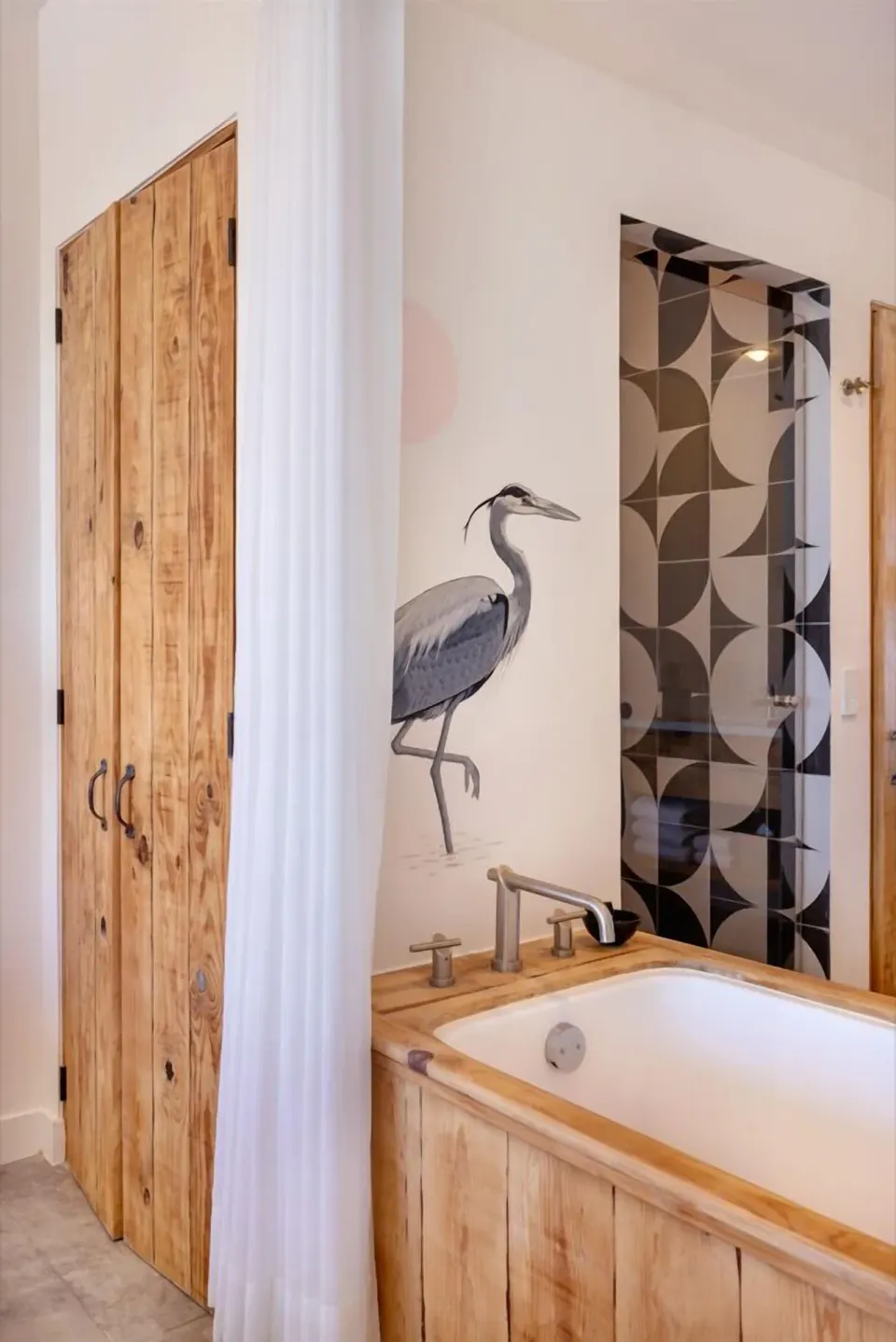 Wood-paneled soaking tub and heron mural in an Ocean View Two Beds room at Hotel El Ganzo.