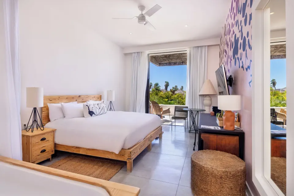 Terrace room with king bed, balcony seating, and mural wall at Hotel El Ganzo.