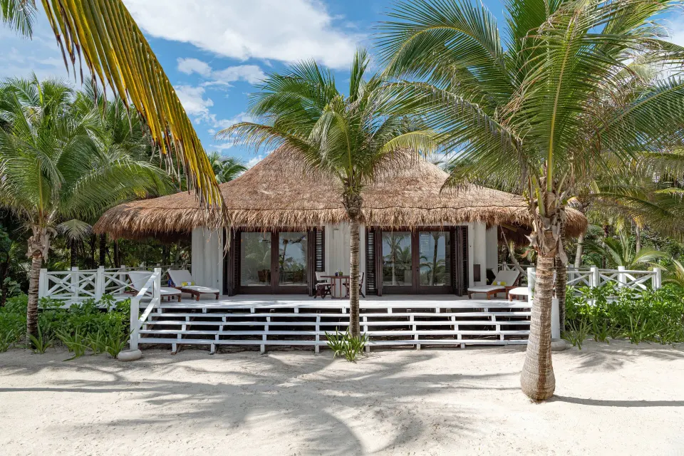 Thatched beachfront villa facade at Hotel Esencia with shaded terrace.