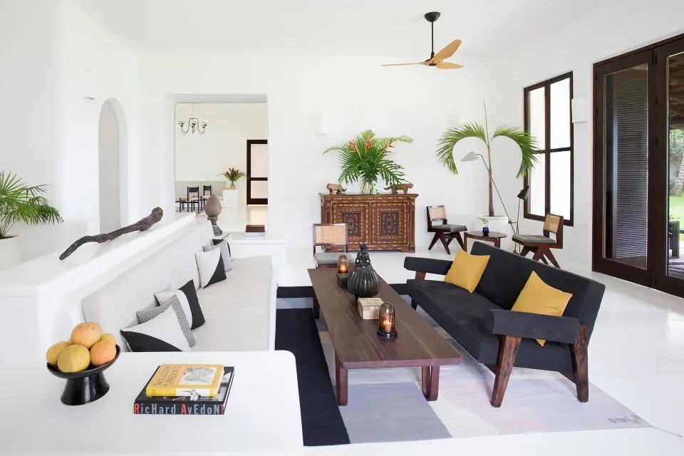 White living room with long built-in sofa and dark wood coffee table at Hotel Esencia.