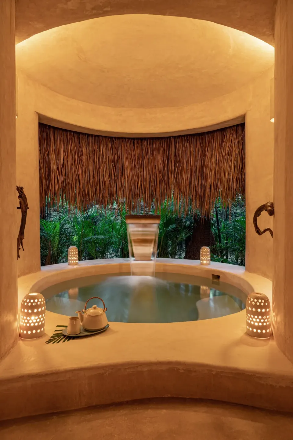 Round indoor spa tub framed by thatch and lanterns at Hotel Esencia