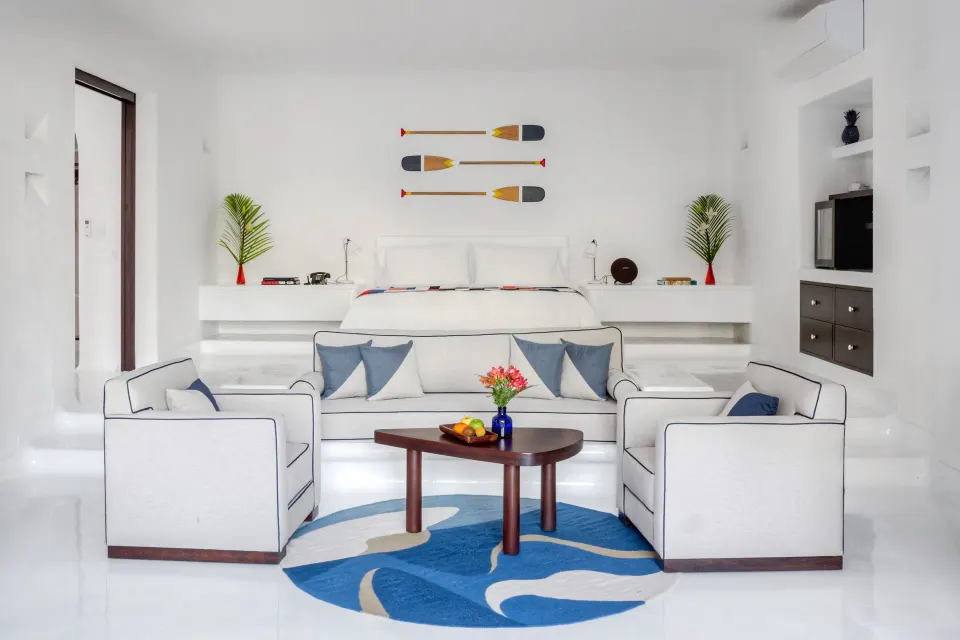 Coastal-themed suite with king bed, sitting area and decorative oars on the wall at Hotel Esencia.