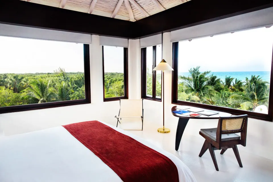 Bright corner guest room with panoramic windows and ocean view at Hotel Esencia.