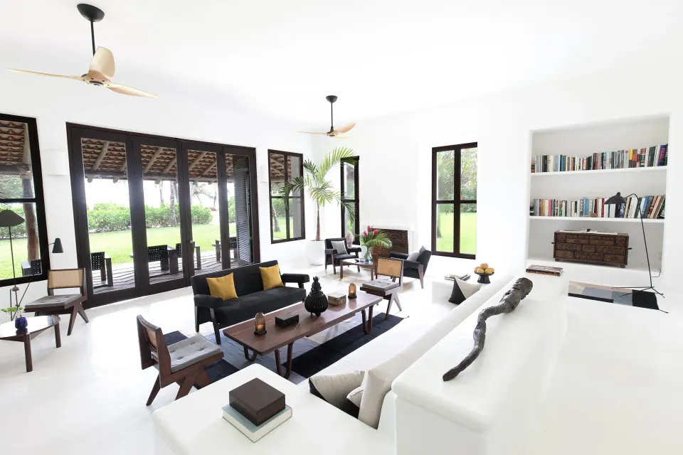 Wide white living room with large windows, built-in seating and bookcase at Hotel Esencia.