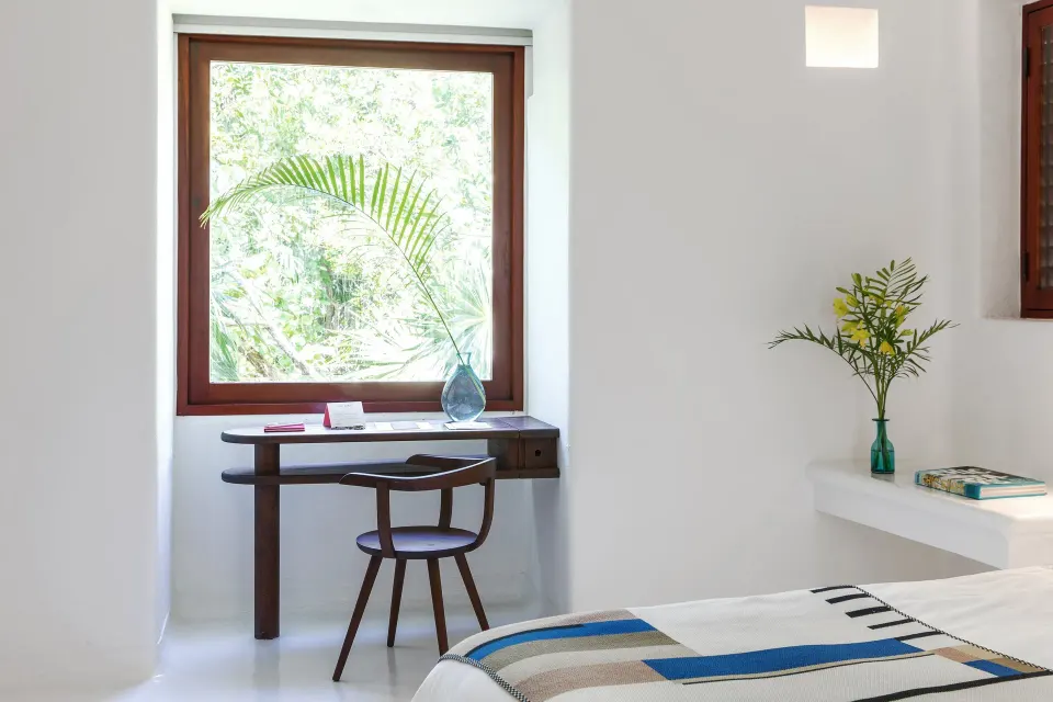 Bright Hotel Esencia guest room corner with desk and window view.