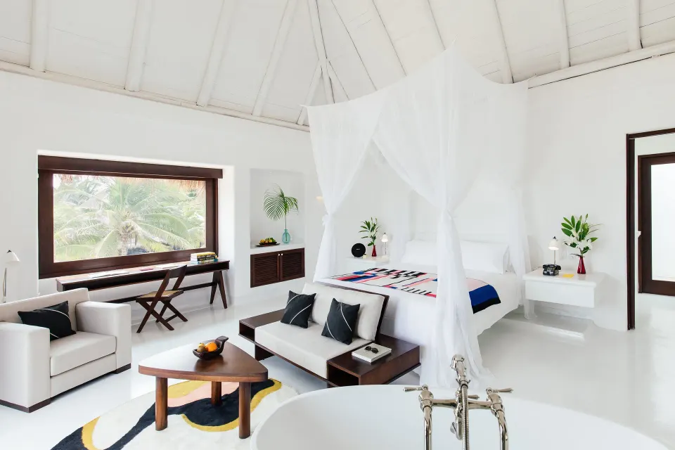 Canopy king bed suite with seating area and large window at Hotel Esencia.