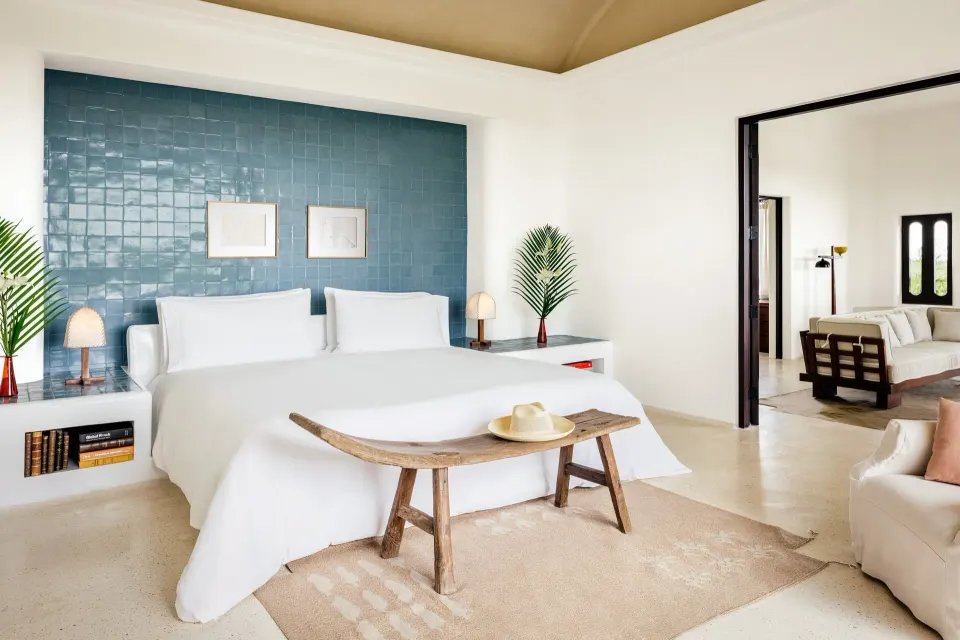 Bright bedroom with king bed, blue tiled headboard and natural decor at Hotel Esencia