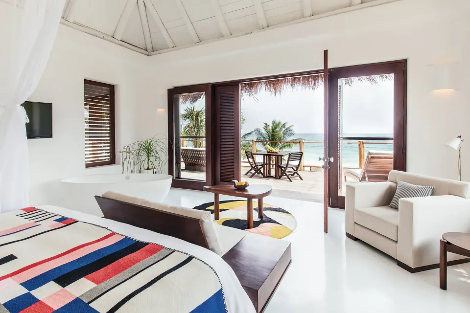 Bright seaside suite with king bed and terrace overlooking the ocean at Hotel Esencia.