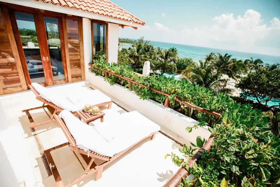 Sun loungers on a private terrace overlooking palms and ocean at Hotel Esencia.