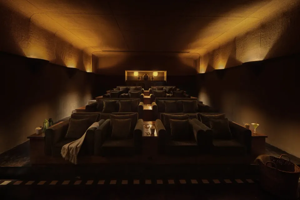 Low-lit spa relaxation or screening room with tiered chaise lounges at Hotel Esencia