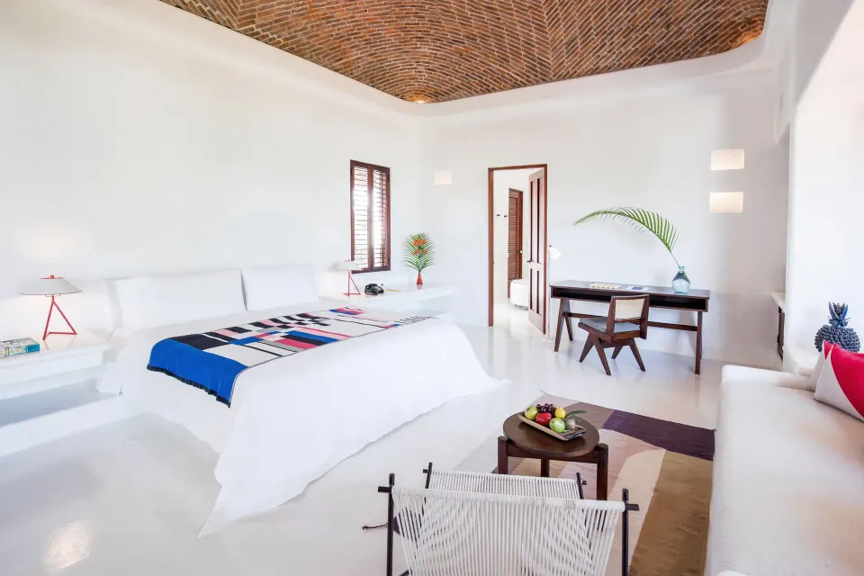 Spacious bedroom with vaulted brick ceiling and seating area at Hotel Esencia.
