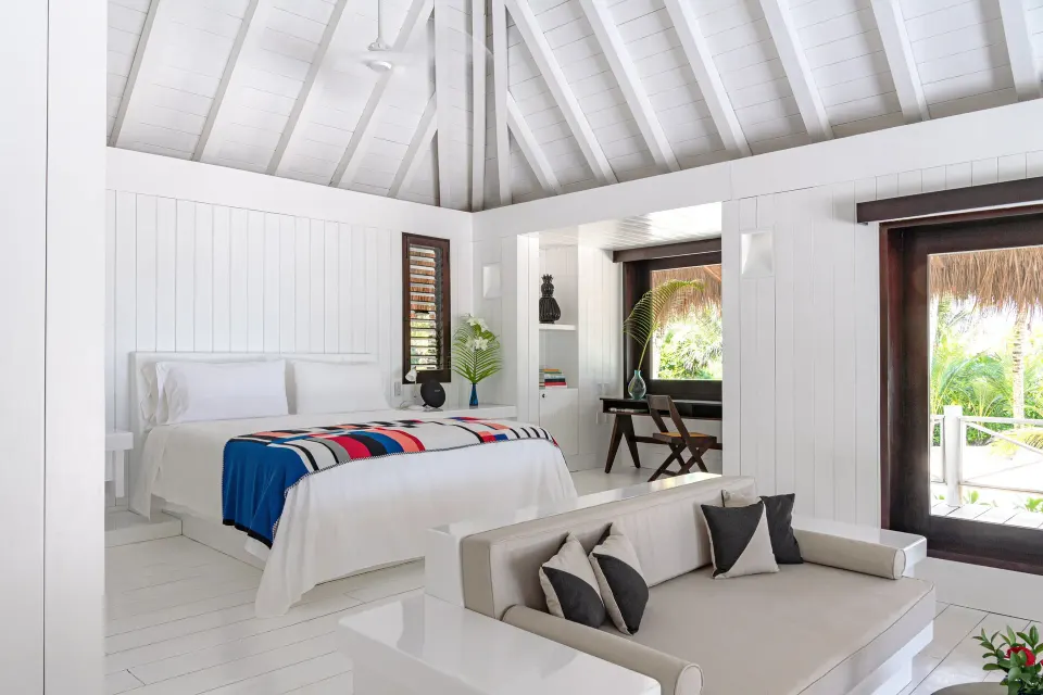 Bright white suite interior with king bed, vaulted ceiling and daybed at Hotel Esencia
