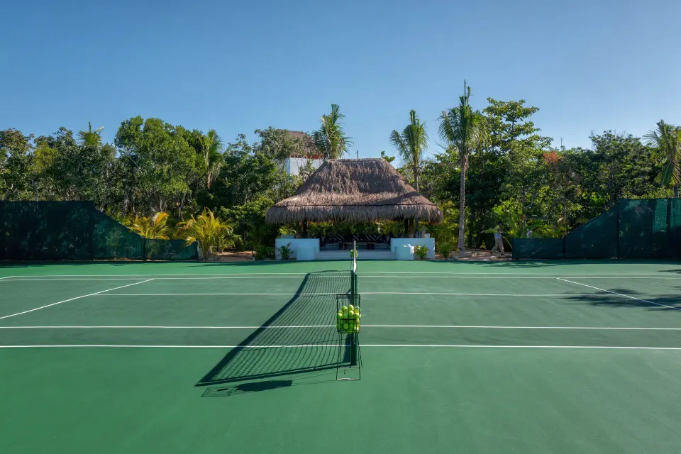 Tennis court net and green playing surface at Hotel Esencia
