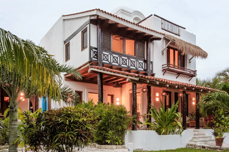 Two-story white villa building with balconies and tropical landscaping at Hotel Esencia