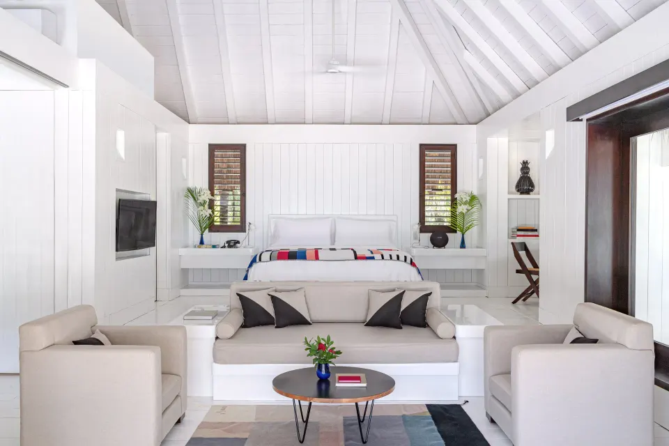 Bright white villa-style room with sofa seating facing a bed at Hotel Esencia.