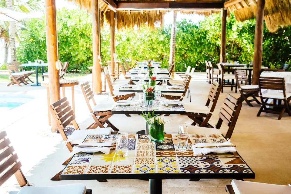 Covered outdoor dining with patterned tile tables at Hotel Esencia