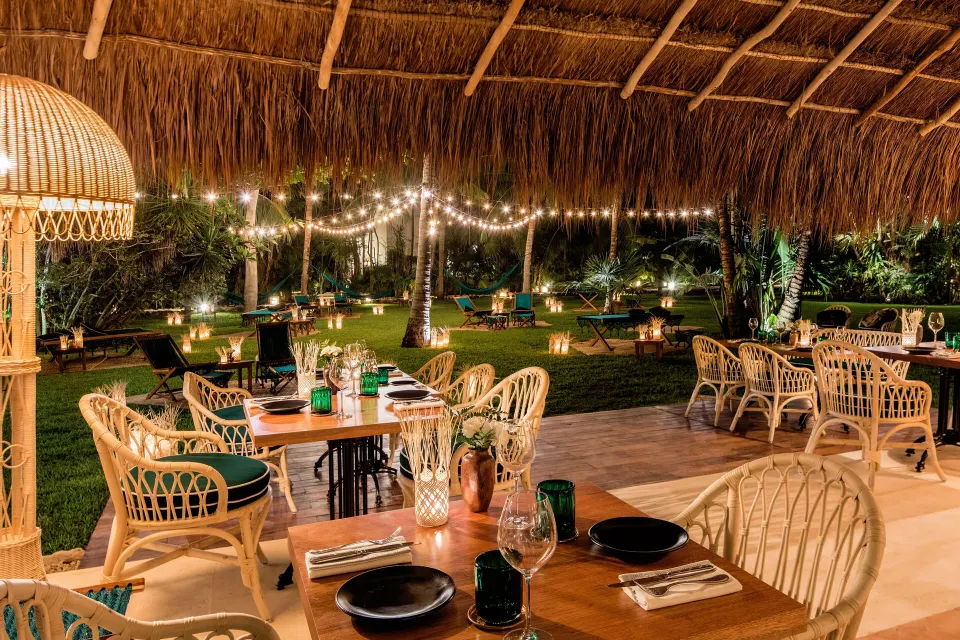 Alfresco dining under string lights and a palapa at Hotel Esencia.