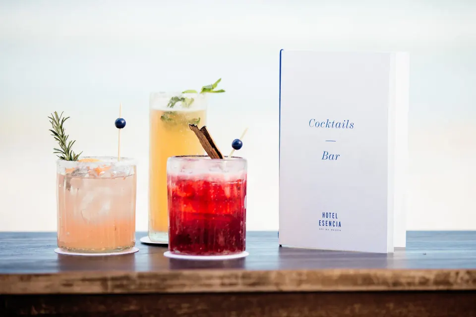 Three colorful cocktails and a menu reading 'Cocktails Bar' at Hotel Esencia