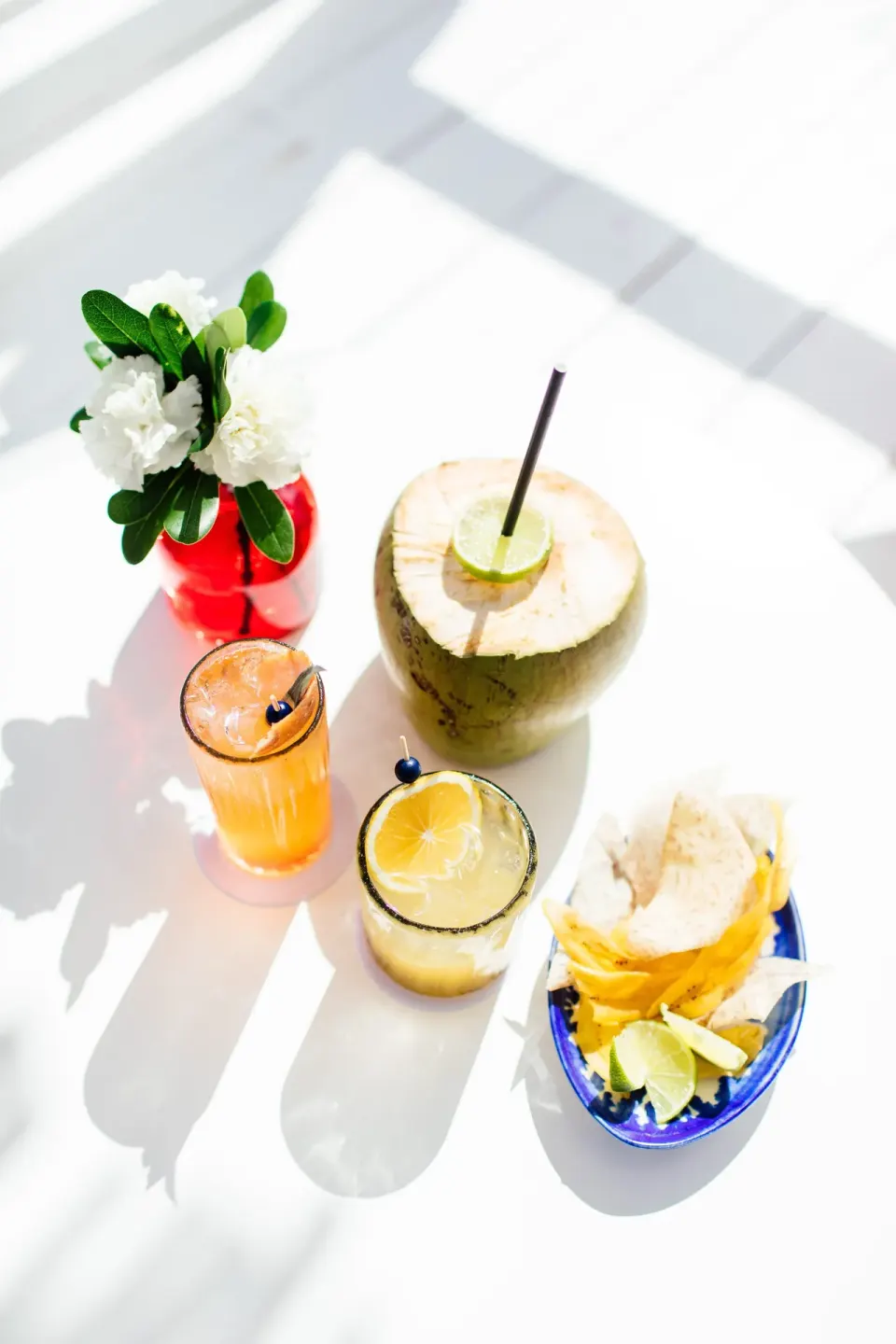 Coconut and colorful cocktails with a small snack on a bright table at Hotel Esencia.
