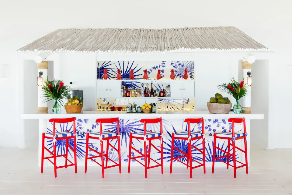 Bright white beach-style bar with red stools at Hotel Esencia.