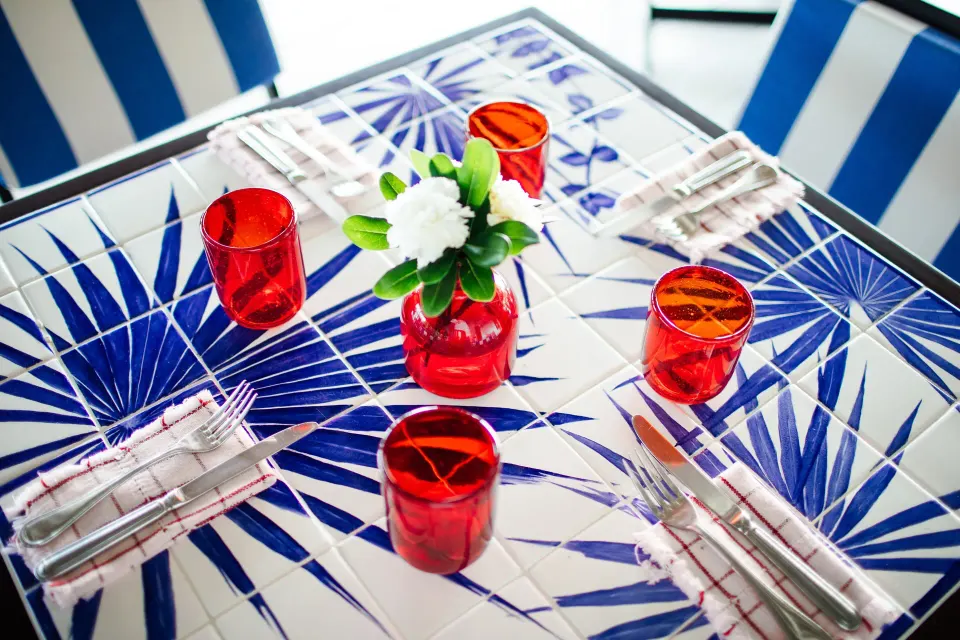 Blue-tiled table set with red glassware at Hotel Esencia